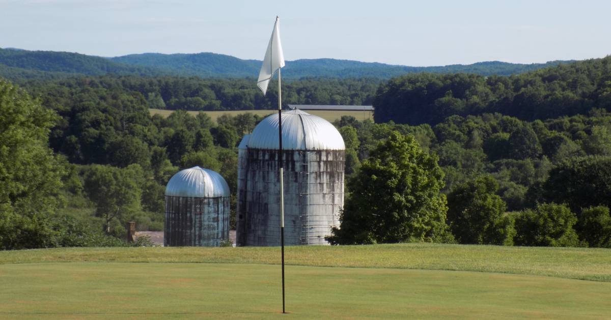 golf hole on course with farm building in the background view