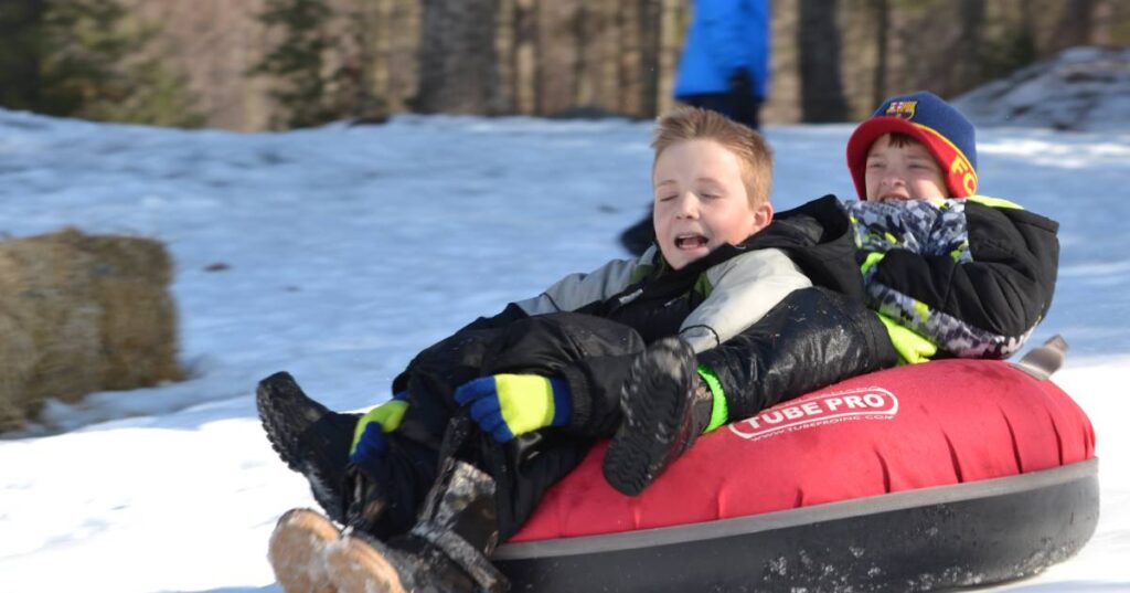 two boys in a snow tube going down a hill