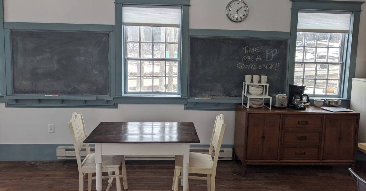 schoolhouse room with a table and chalkboards and windows
