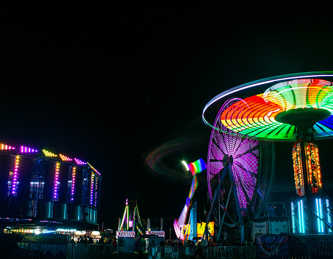 Carnival rides with bright lights against a night clear sky