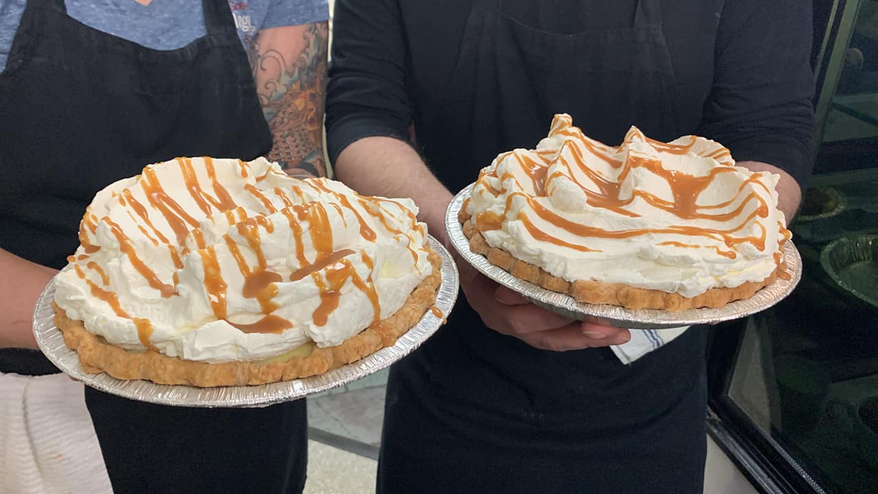 Two servers holding pies at Greenwich Village Cafe and Bakery