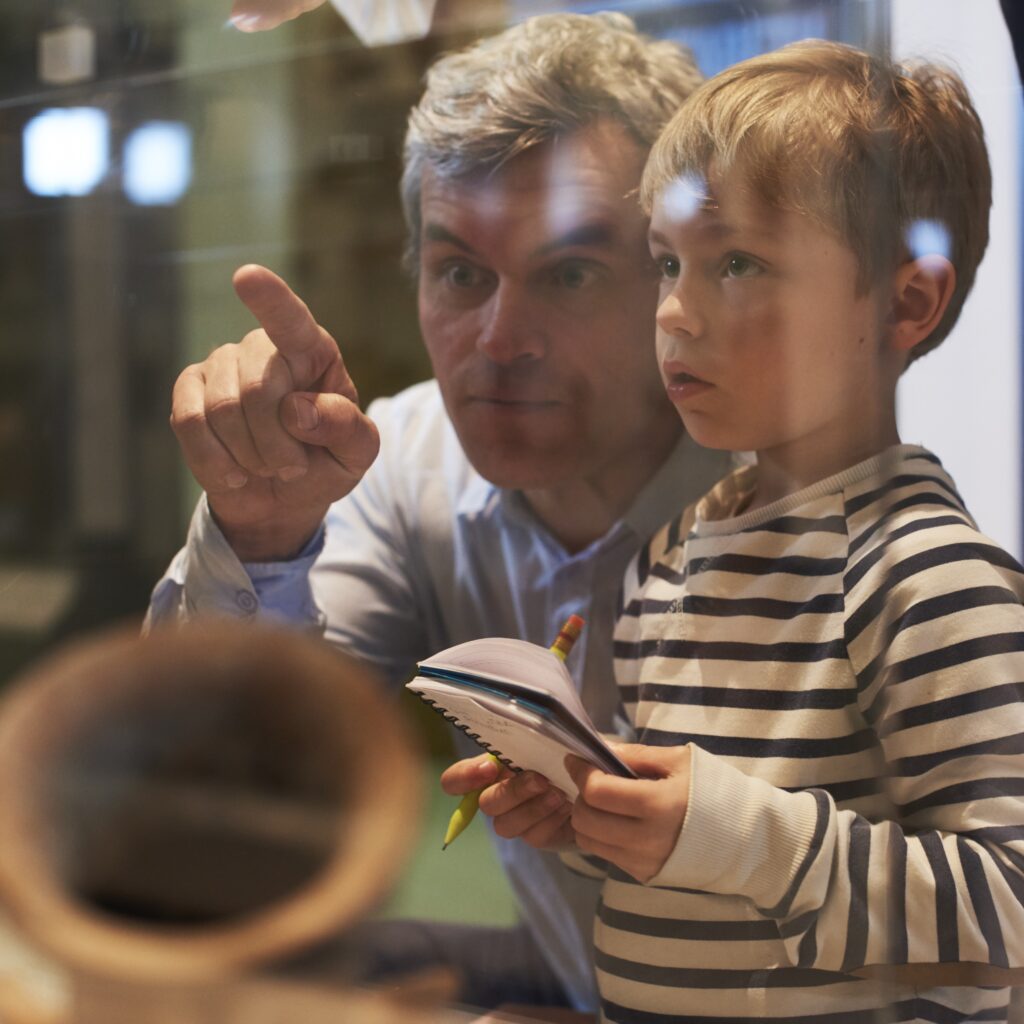 Child and man looking at artifacts in museum. Discover local history at Living History Weekend in Fort Edward, NY.